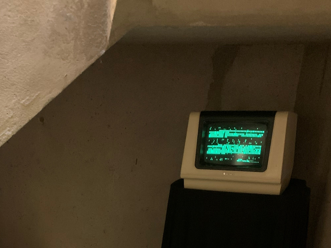 A 1980s computer terminal with garbled green characters on a black background