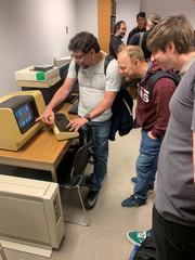 A small group gathered around a VT125 terminal connected to a micro PDP11